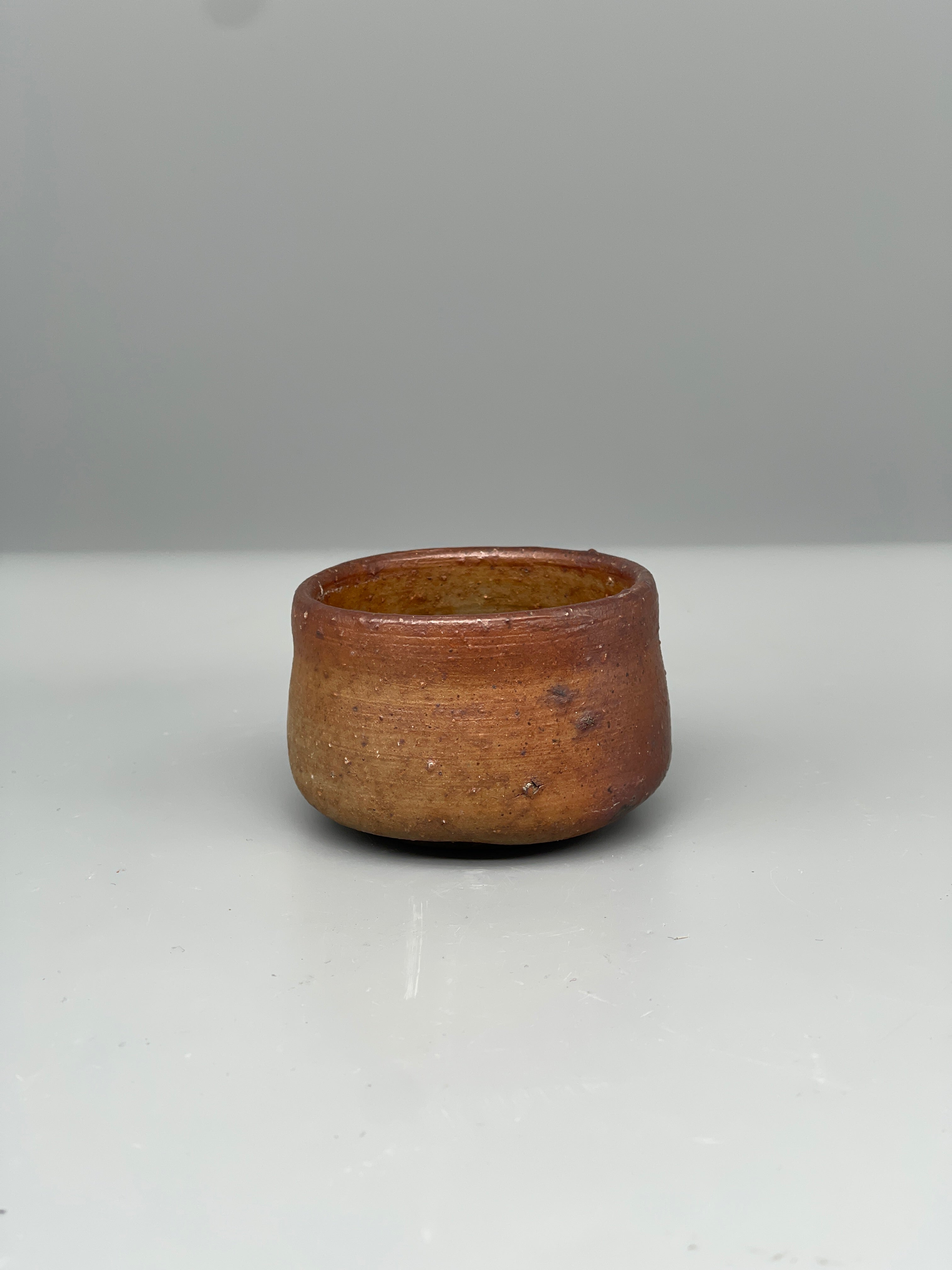 Vintage Japanese bizen guinomi cup, rust red, angled view