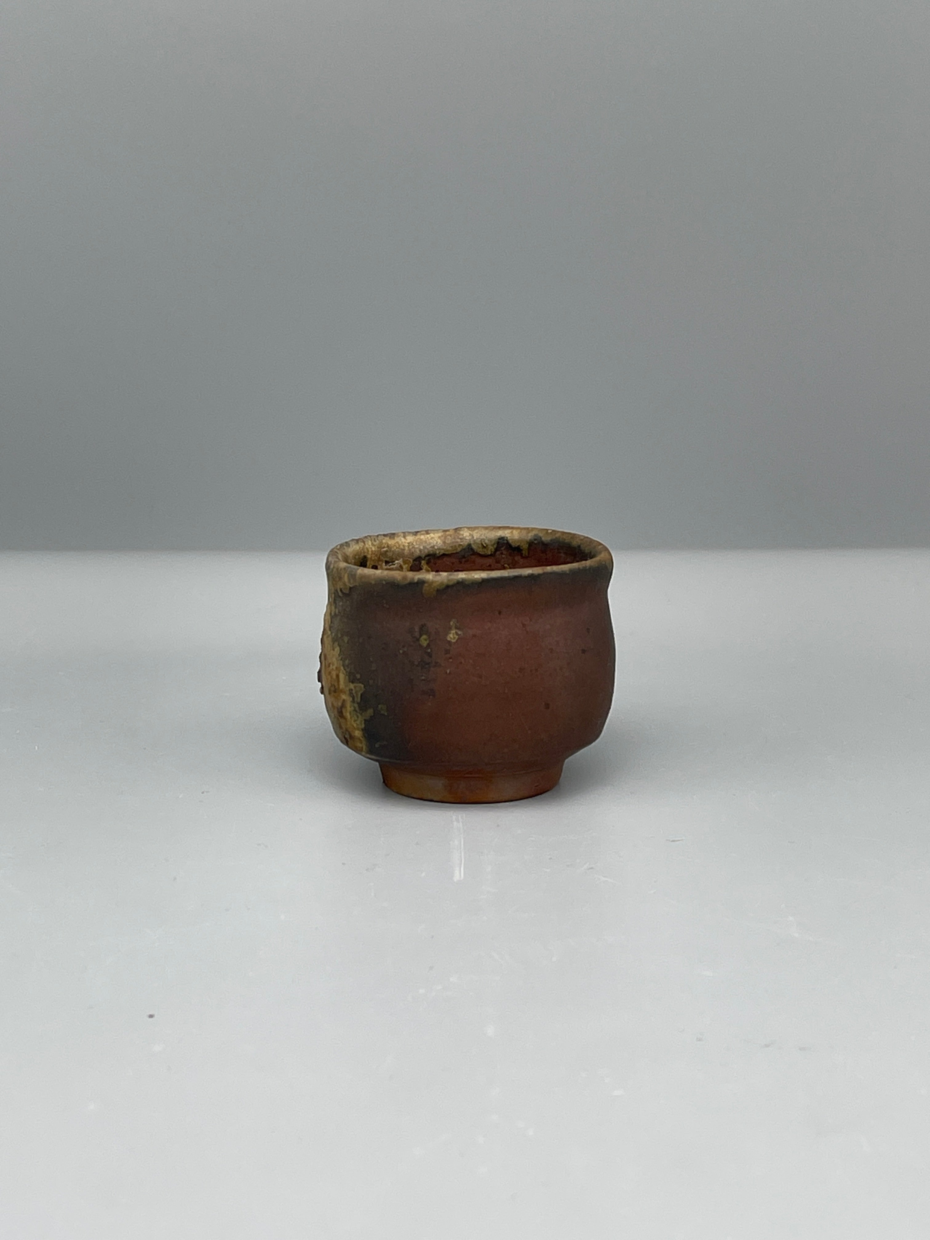 Vintage Japanese bizen guinomi cup, ash-crusted rim, angled view