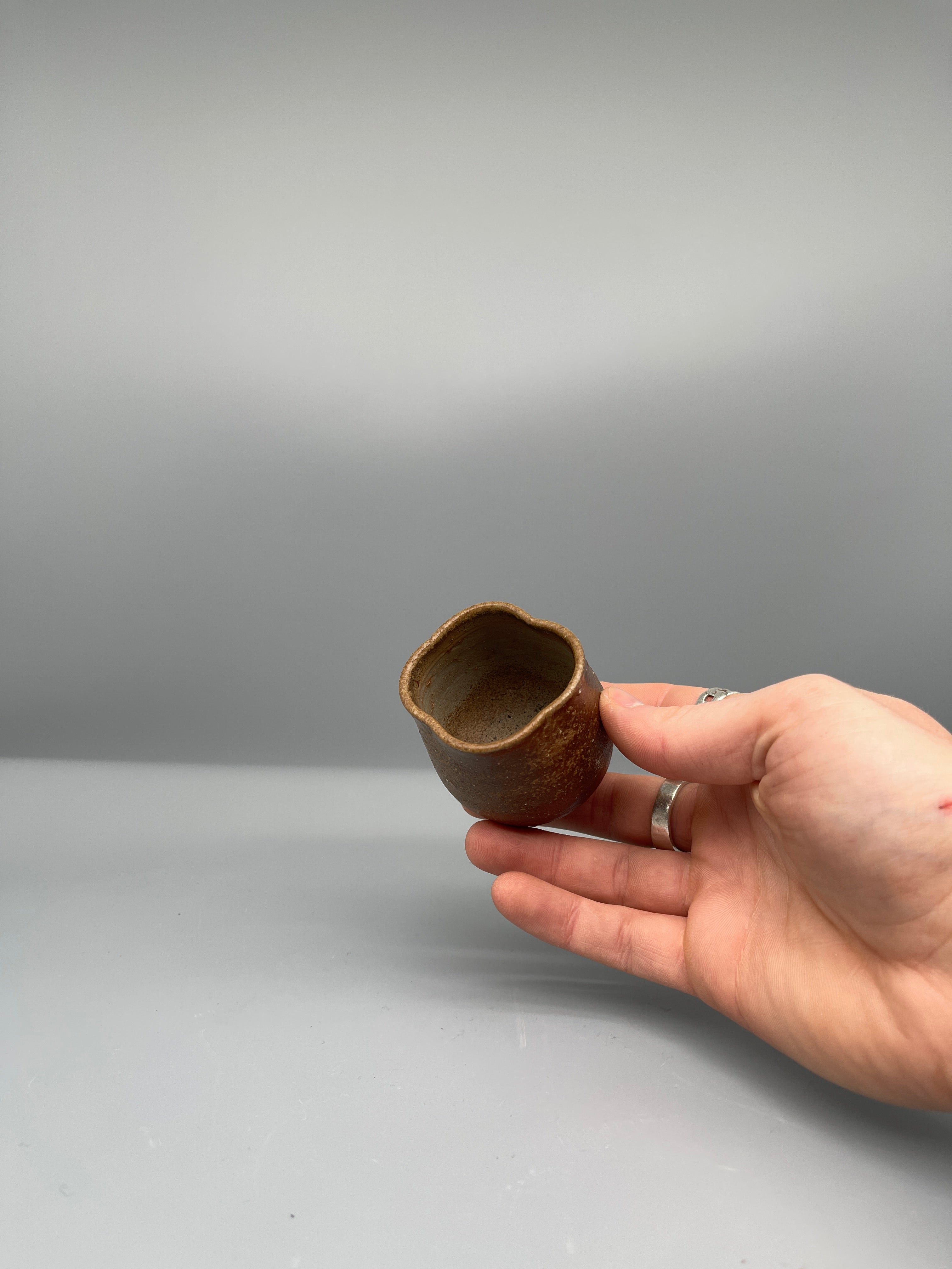 Vintage Japanese bizen guinomi cup, speckled red, held closer