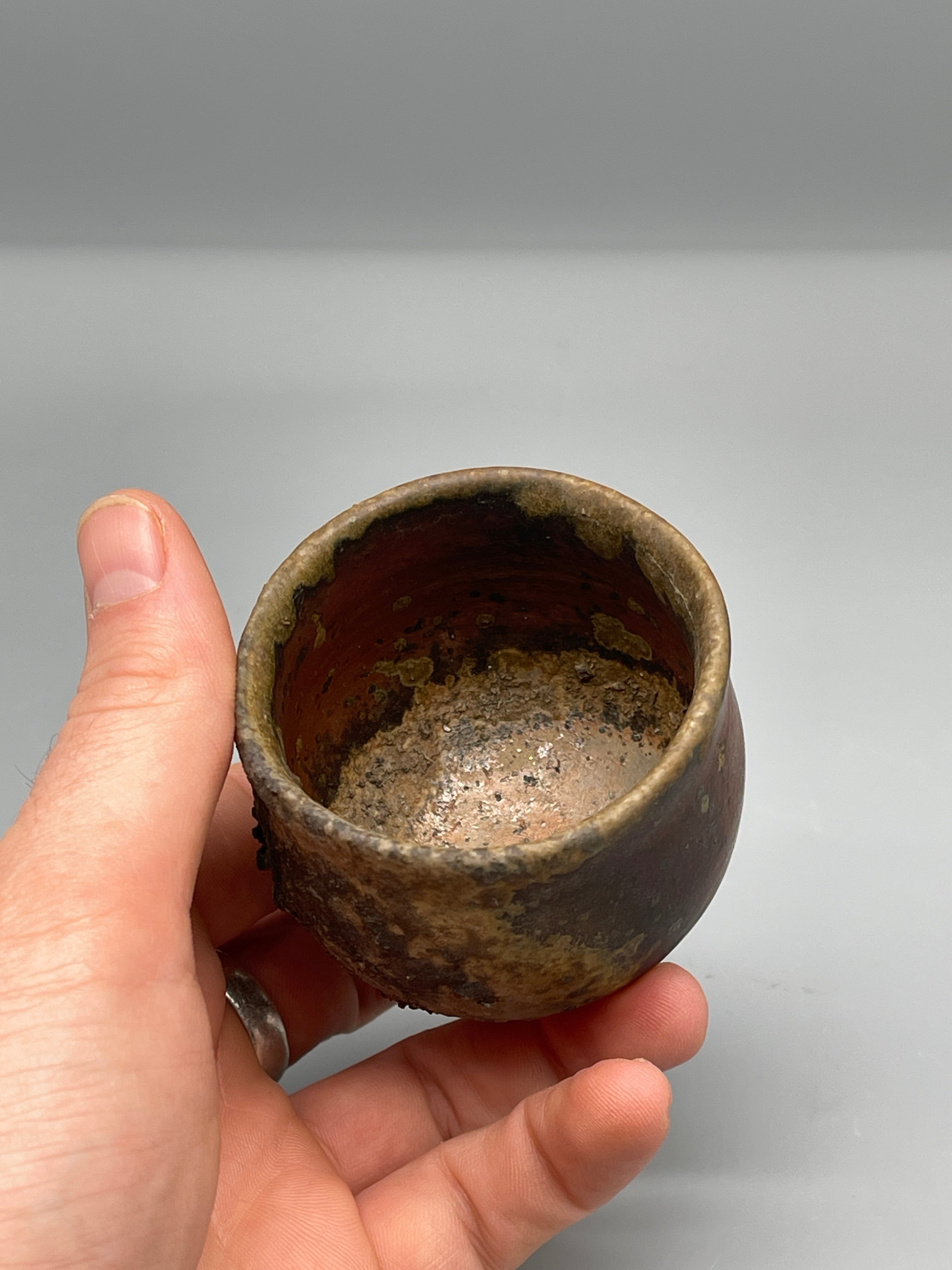 Vintage Japanese bizen guinomi cup, gold-flecked, held with interior view