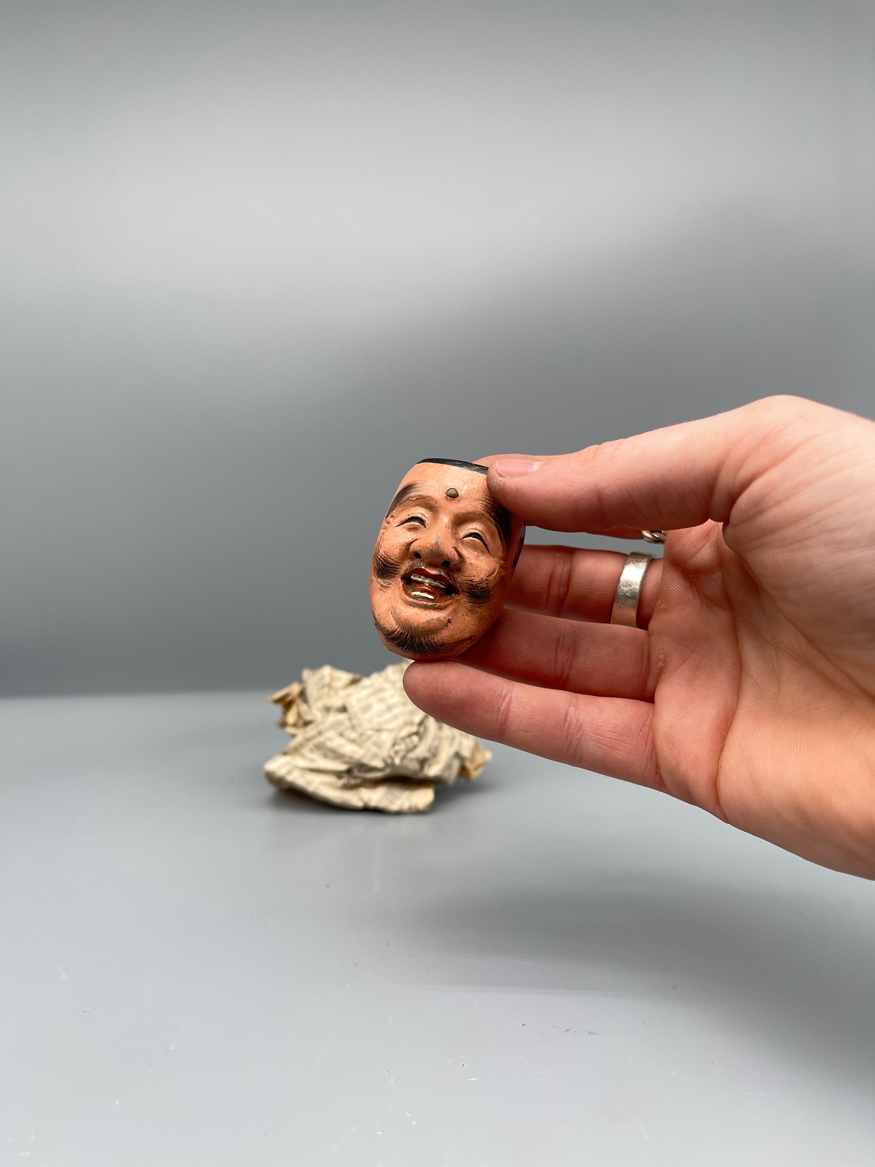 Vintage Japanese carved mask, smiling face, held view
