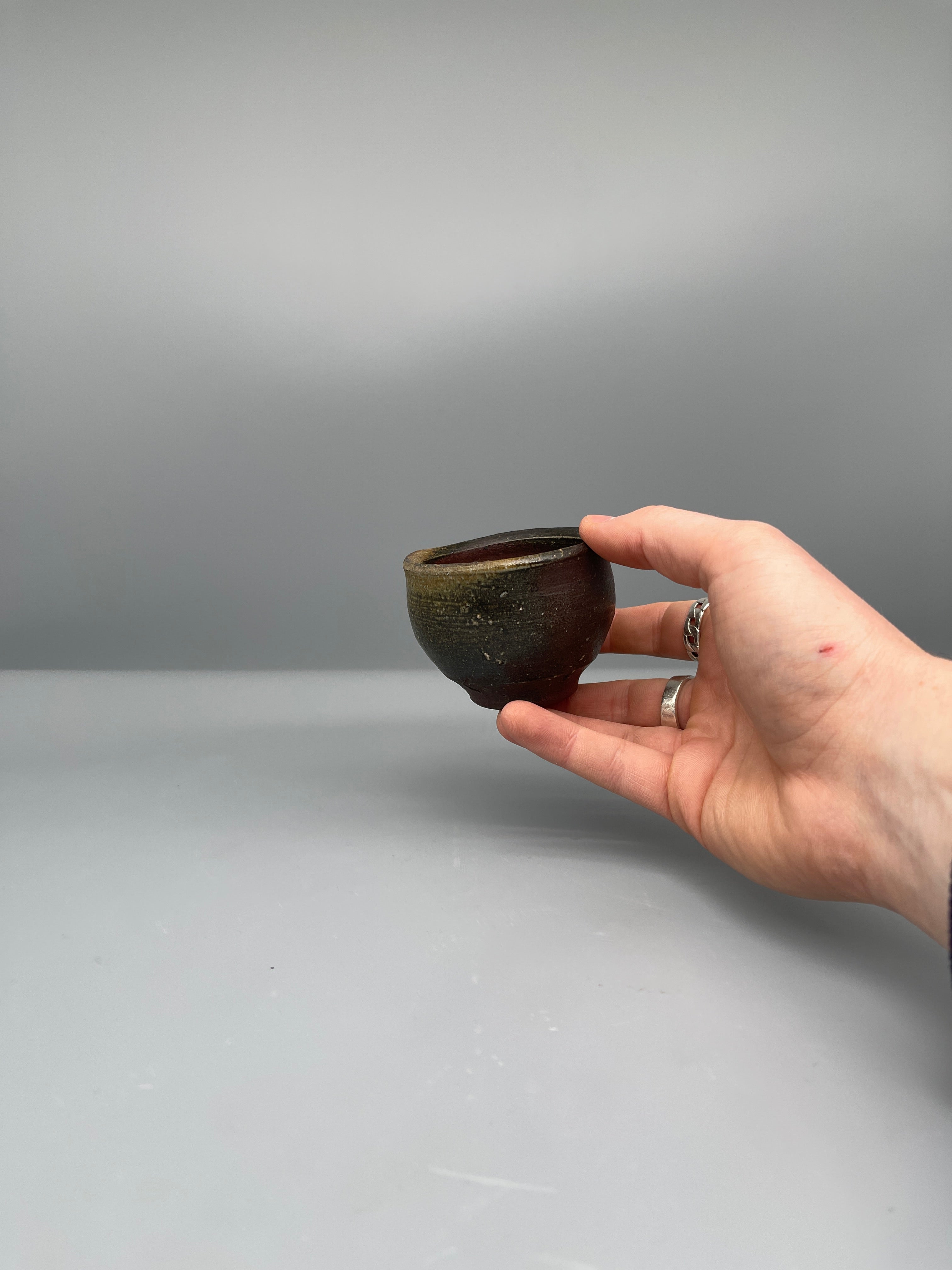 Vintage Japanese bizen guinomi cup, speckled red, held for scale