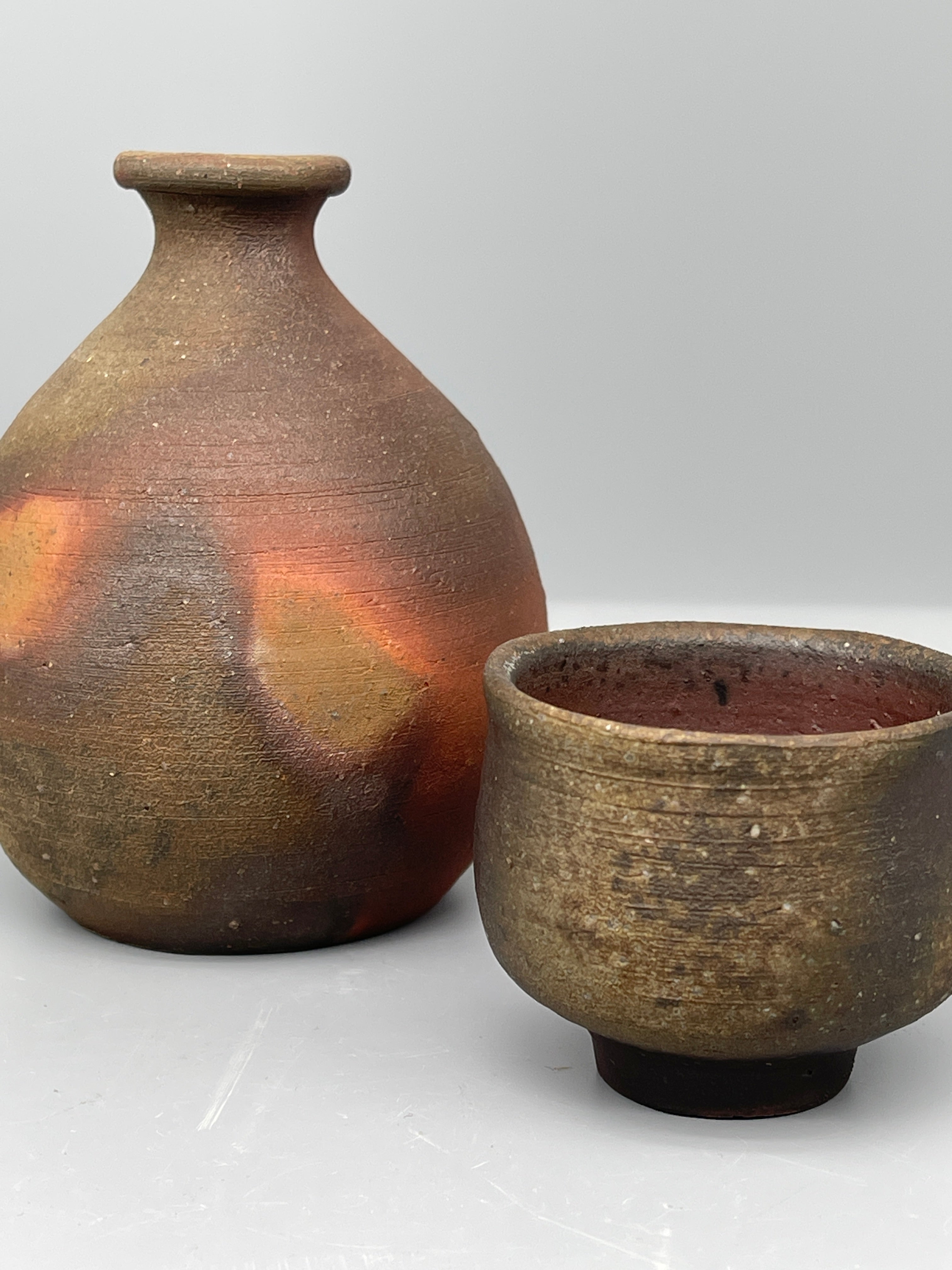 Vintage Japanese bizen sake bottle and cup, side by side