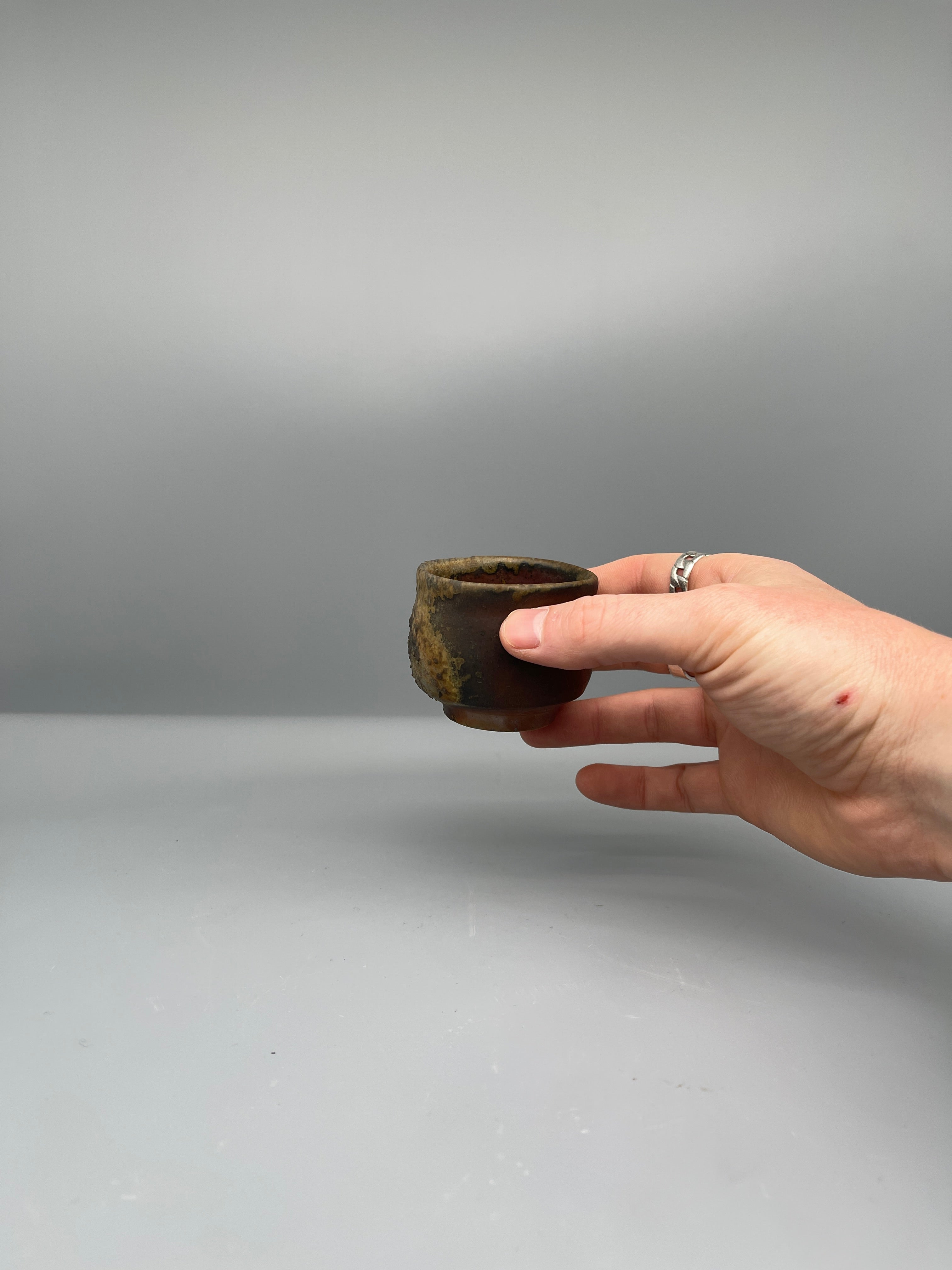 Vintage Japanese bizen guinomi cup, ash-crusted rim, held for scale