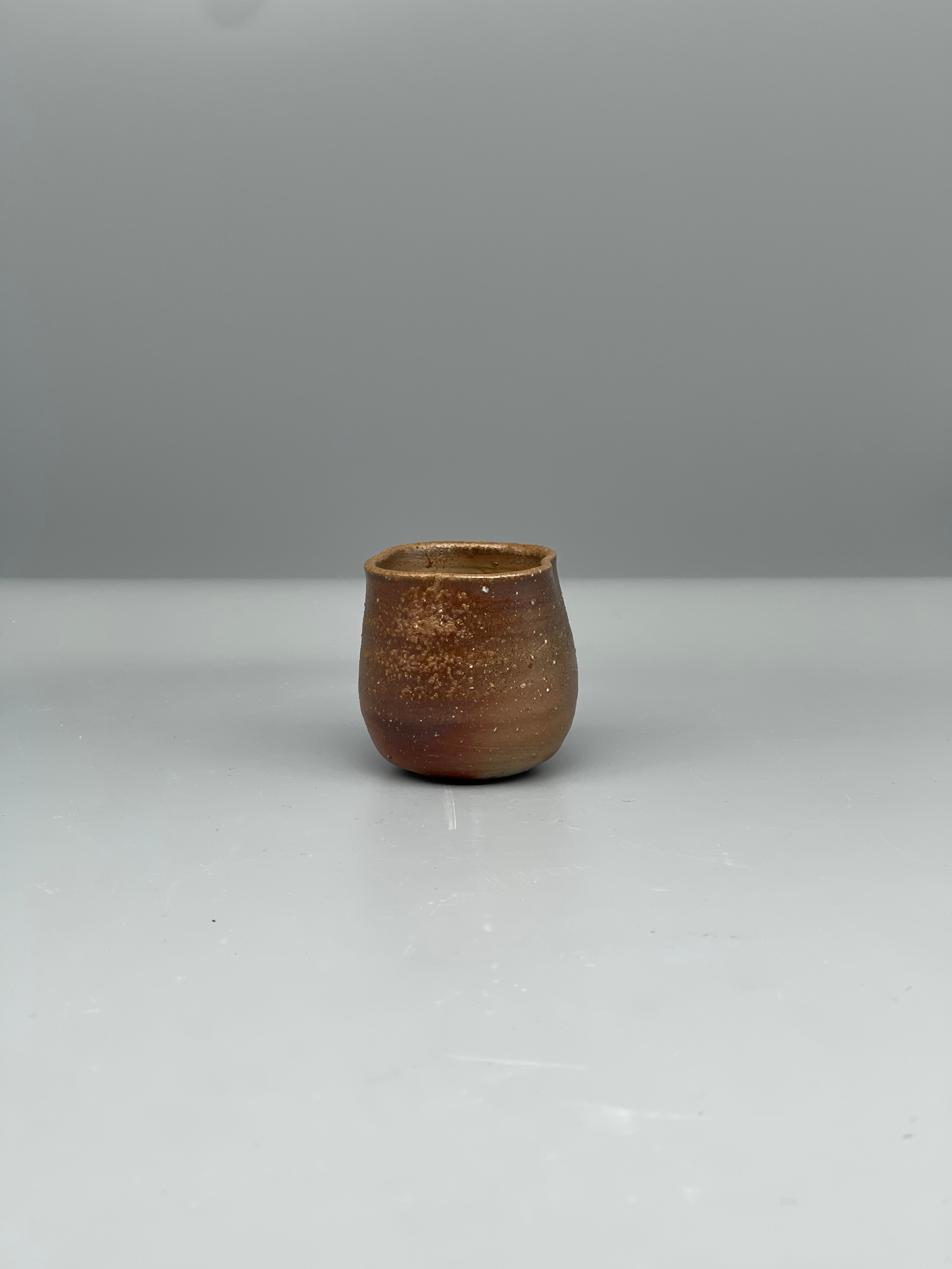 Vintage Japanese bizen guinomi cup, speckled red, angled view