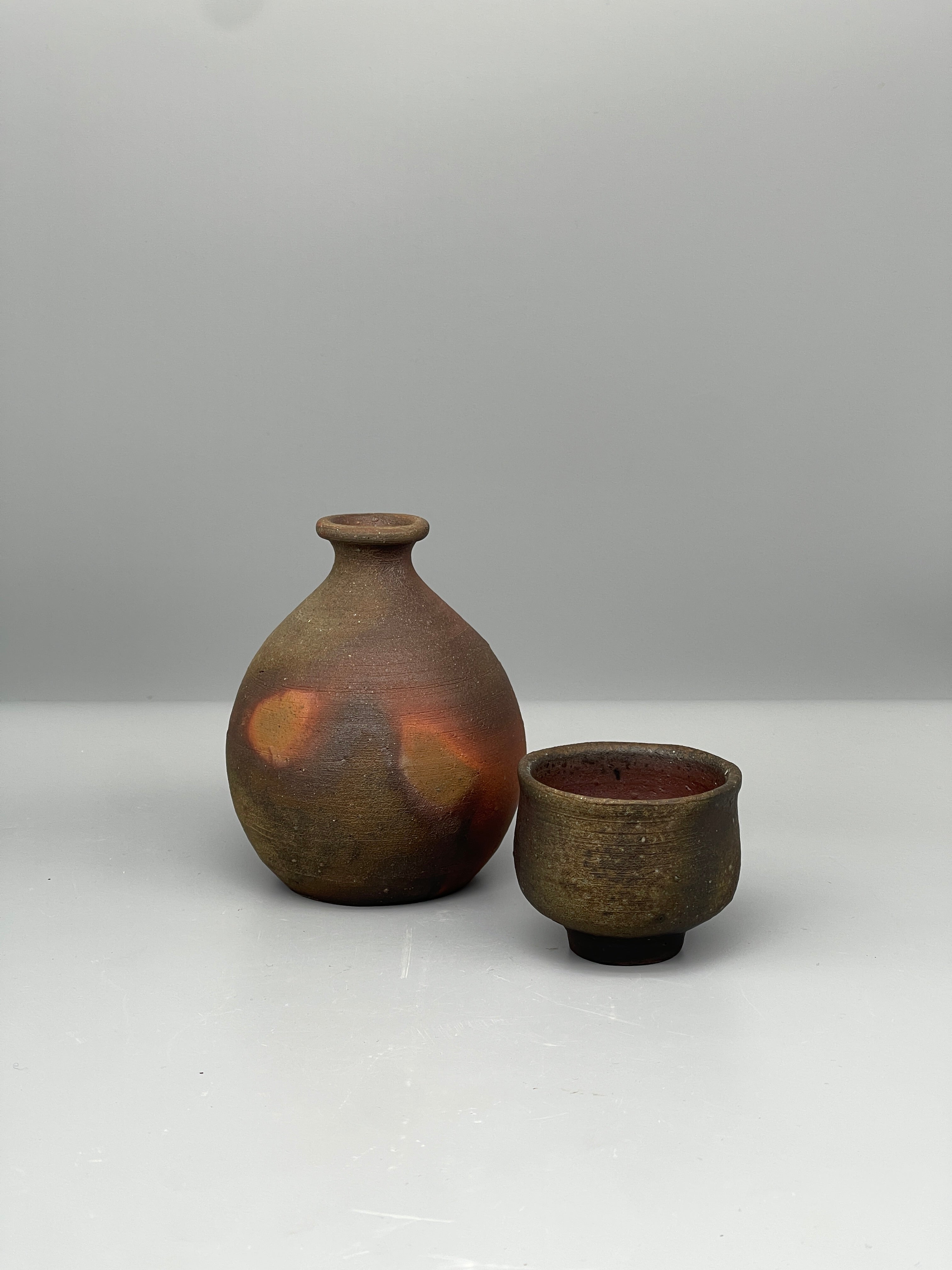 Vintage Japanese bizen sake bottle held, with cup